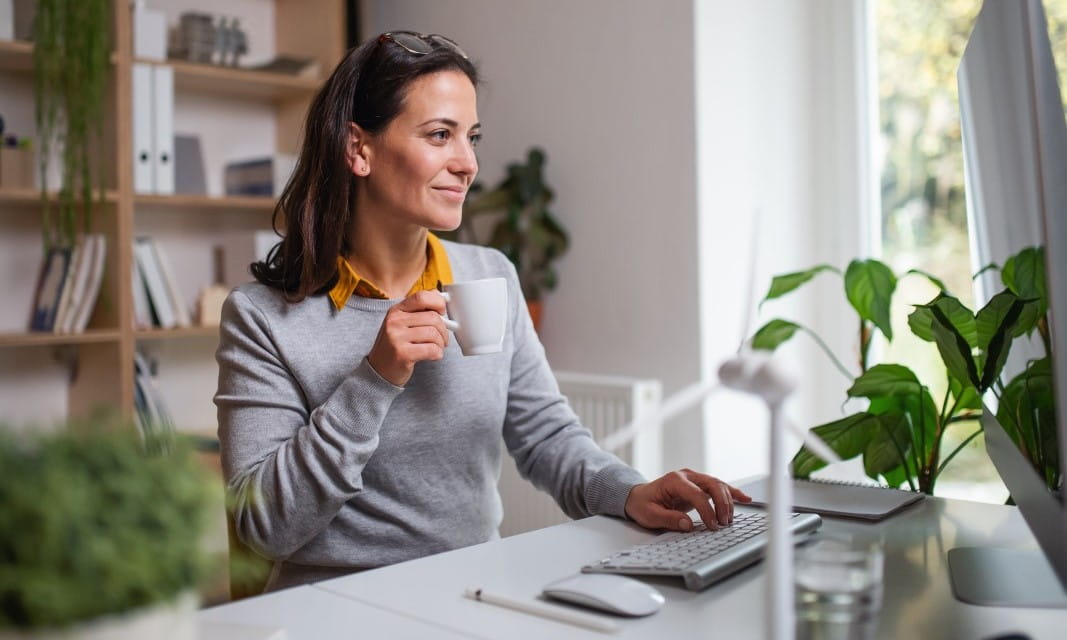 Woman drinking from mug at workstation