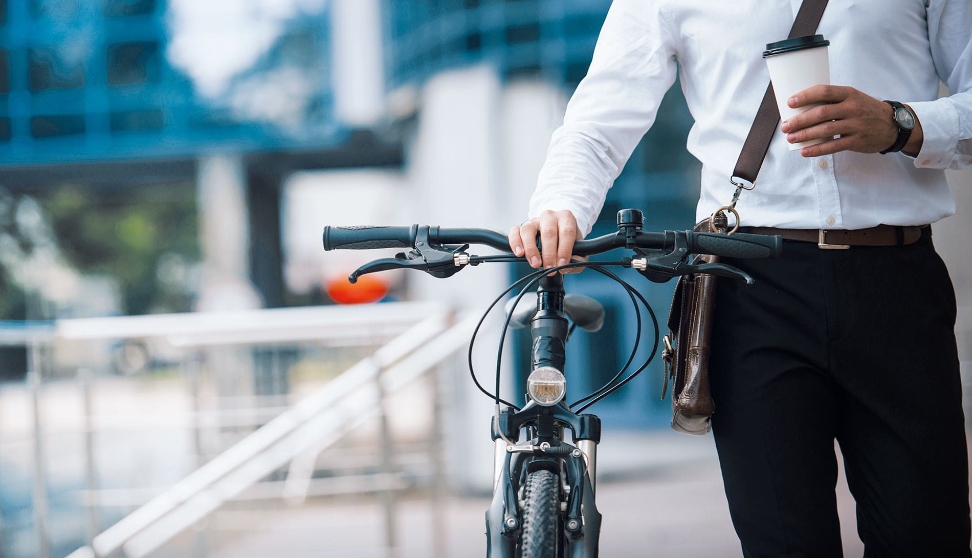 Man holding bike handlebars and a coffee cup