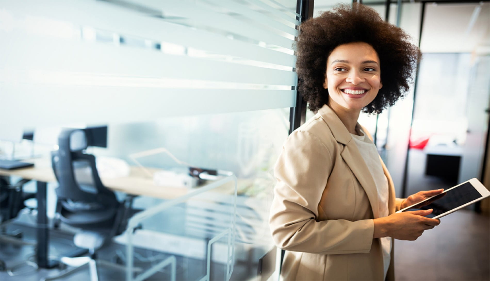 Smiling woman in office holding tablet device